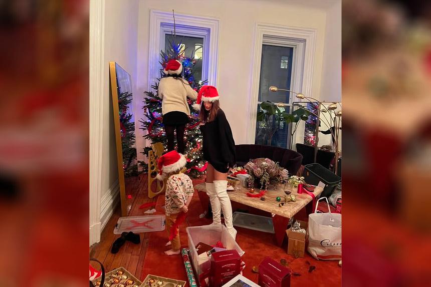 Модель Эмили Ратаковски станцевала в сапогах и свитере на фоне новогодней елки